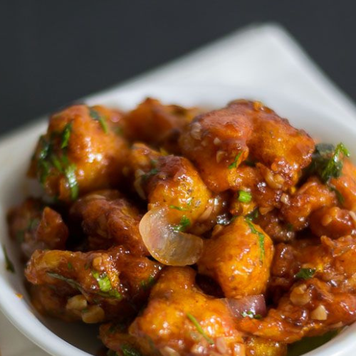 Gobi Manchurian Recipe | crispy & saucy restaurant style final presentation of gobi manchurian served on a dining table with chopstick at zaikastreet restaurant